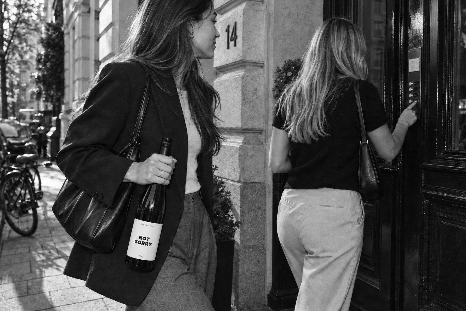 Zwei Frauen vor einer Altbautür, eine trägt die Flasche in der Hand